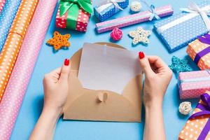 Top view of woman holding an envelope on blue background made of holiday decorations. Christmas time concept photo