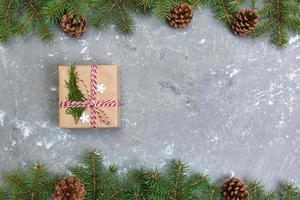 Christmas background with fir tree and gift box on gray cement table. Top view with copy space for your design photo