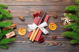 Top view of utensils on festive napkin on wooden background. Christmas decorations with dried fruits and cinnamon. Close up of New year dinner concept photo