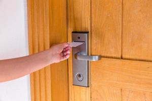 mano femenina colocando y sosteniendo el interruptor de la tarjeta de llave magnética para abrir la puerta de la habitación del hotel foto