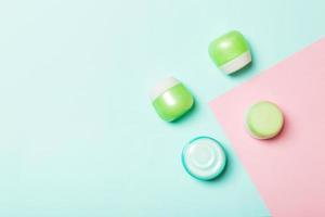 Top view of cosmetic containers, sprays, jars and bottles on pink background. Close-up view with empty space for your design photo