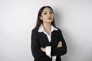 Portrait of a confident smiling Asian girl boss wearing black suit standing with arms folded and looking at the camera isolated over white background photo