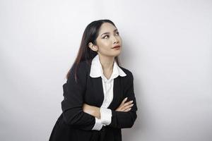 Portrait of a confident smiling Asian girl boss wearing black suit standing with arms folded and looking at the camera isolated over white background photo