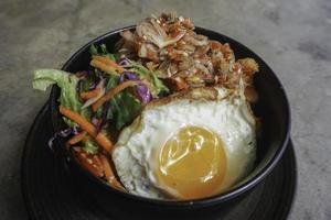 A portrait of a rice bowl with Balinese sauce called sambal matah on a black bowl isolated by concrete background photo