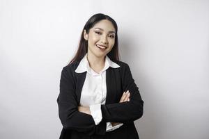 Portrait of a confident smiling Asian girl boss wearing black suit standing with arms folded and looking at the camera isolated over white background photo