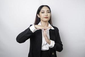 mujer de negocios asiática hispana con traje negro haciendo gestos de tiempo fuera con las manos, cara frustrada y seria foto