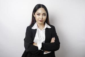 Portrait of a confident smiling Asian girl boss wearing black suit standing with arms folded and looking at the camera isolated over white background photo