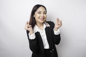 An attractive young Asian woman wearing a black suit feels happy and a romantic shapes heart gesture expresses tender feelings photo