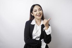 Excited Asian businesswoman wearing black suit gives thumbs up hand gesture of approval, isolated by white background photo