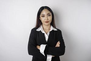 Portrait of a confident smiling Asian girl boss wearing black suit standing with arms folded and looking at the camera isolated over white background photo