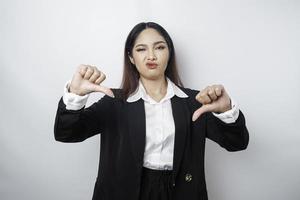 una mujer de negocios asiática decepcionada da un gesto de desaprobación con la mano hacia abajo, aislada por un fondo blanco foto