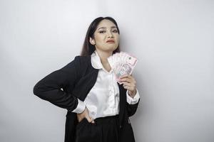 A portrait if a young businesswoman with a stack of money in Indonesian Rupiah in her hands isolated by white background photo