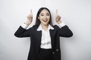 emocionada mujer de negocios asiática con traje negro apuntando al espacio de copia encima de ella, aislada de fondo blanco foto