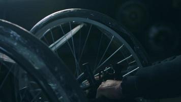 sida se av ett amerikan manlig arbetare i en verkstad på en fabrik framställning rullstolar, Sammanträde på en arbetsbänk använder sig av hand verktyg och montering delar av en produkt, Sammanträde i rullstolar video