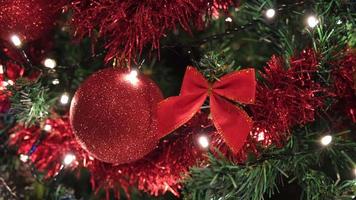 Red bauble and ribbon on a Christmas decorated pine tree video