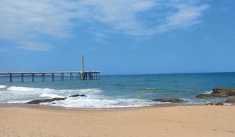 Lifeguard tower on the beach sand with umbrellas, the sea and a blue sky in the background photo