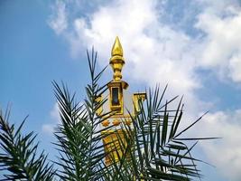 brown gold white color mosque minaret with arabic architecture in madiun indonesia park, sunny weather. photo