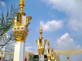 minarete de mezquita de color blanco dorado marrón con arquitectura árabe en el parque madiun indonesia, clima soleado. foto