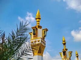 minarete de mezquita de color blanco dorado marrón con arquitectura árabe en el parque madiun indonesia, clima soleado. foto