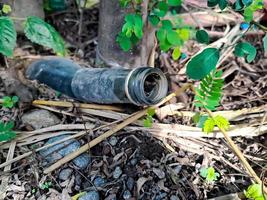 botellas de jarabe usadas incrustadas en el suelo con hierba verde entre las botellas. foto