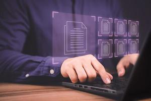 Document Management System, online documentation database and process automation to efficiently manage files. Corporate business technology. Employee man using a computer laptop in office. photo