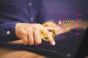 Man hand using computer laptop with popup five star icon for feedback review satisfaction service, testimonial. Customer service experience and business satisfaction survey. photo