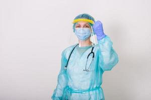 médico, enfermera con traje de protección para combatir el coronavirus covid-19 con antecedentes blancos. trabajador médico con traje protector y protector facial levantando el puño para combatir el brote de coronavirus foto