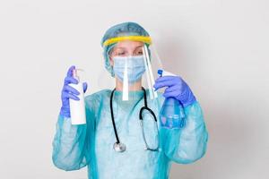 Woman wearing gloves, biohazard protective suit, face shield and mask with hand sanitizer bottle and disinfection gel. corona virus or Covid-19 protection. photo