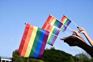 Rainbow flags, LGBT symbol, holding in hands, concept for LGBT community celebration in pride month, June, 2023, around the world. photo