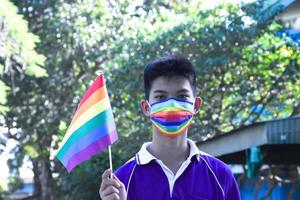 Portrait Asian young boy holds rainbow flag, LGBT symbol, in hands while joining his LGBT activity at school, concept for LGBT community celebration in pride month, June, 2023, around the world. photo