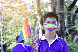 Portrait Asian young boy holds rainbow flag, LGBT symbol, in hands while joining his LGBT activity at school, concept for LGBT community celebration in pride month, June, 2023, around the world. photo