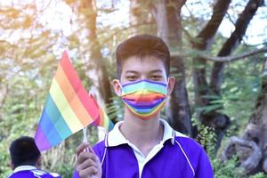 Portrait Asian young boy holds rainbow flag, LGBT symbol, in hands while joining his LGBT activity at school, concept for LGBT community celebration in pride month, June, 2023, around the world. photo