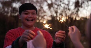 enfoque selectivo, el joven disfruta de jugar fuegos artificiales quemando bengalas con su novia en el festival de año nuevo, se ríen felices en la noche de fiesta de año nuevo al aire libre video