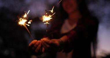 selettivo messa a fuoco un' fuoco d'artificio ardente sparkler nel femmina mani nel nuovo anno Festival, lei godere per giocando scintillante nel mano su nuovo anni festa notte video