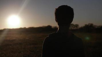 silhouet, tiener- jongen, jong Mens aan het kijken de zonsondergang video