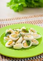 Boiled quail eggs halves on a green plate photo