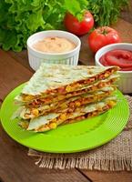 Mexican Quesadilla sliced with vegetables and sauces on the table photo