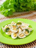 Boiled quail eggs halves on a green plate photo