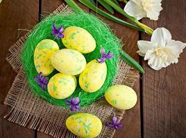Easter eggs and flowers on wooden background photo