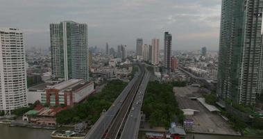 luftaufnahme der taksin-brücke und des sathorn road-geschäftszentrums mit transport über den chao phraya-fluss bei sonnenaufgang, bangkok, thailand video