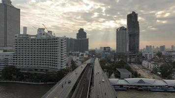 Luftüberschreitung des Verkehrs auf der Taksin-Brücke und dem Geschäftszentrum der Sathorn-Straße über dem Fluss Chao Phraya bei Sonnenaufgang, Bangkok, Thailand