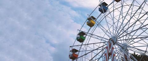 Colorful ferris wheels in the amusement park on a background of blue sky with clouds. Toned image. Bottom view photo