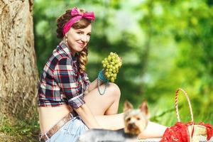 beautiful young girl in a plaid shirt and short denim shorts in pin-up style in forest photo