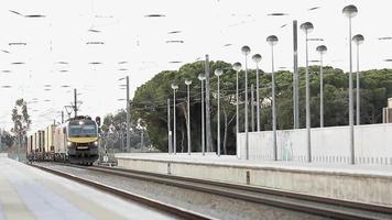 um comboio de mercadorias a chegar à estação de comboios de grandola, em portugal, num dia claro - plano geral video