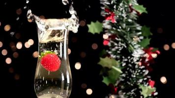 Strawberry falling on champagne at slow motion for Christmas Eve dinner party or New Year Eve video