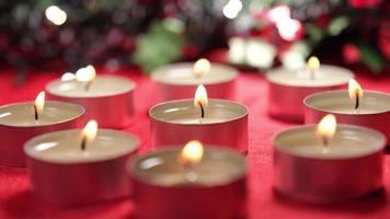 luces de velas de navidad sobre fondo rojo y decoración de guirnaldas de navidad para la celebración religiosa navideña video