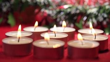 luces de velas de navidad sobre fondo rojo y decoración de guirnaldas de navidad para la celebración religiosa navideña video