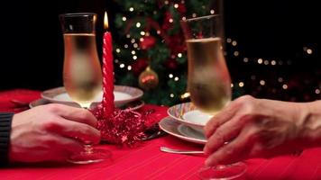 champagner prost beim weihnachtsabendessen auf einem rot gedeckten tisch anstoßen