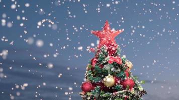 nieve en el pino decorado con navidad durante la noche de la víspera de navidad. invierno nevando a cámara lenta. video