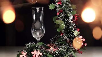 gießen von champagner für das weihnachtsabendessen mit lichtern und girlandendekoration in zeitlupe